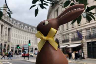Chocolate rabbit held up against a street view