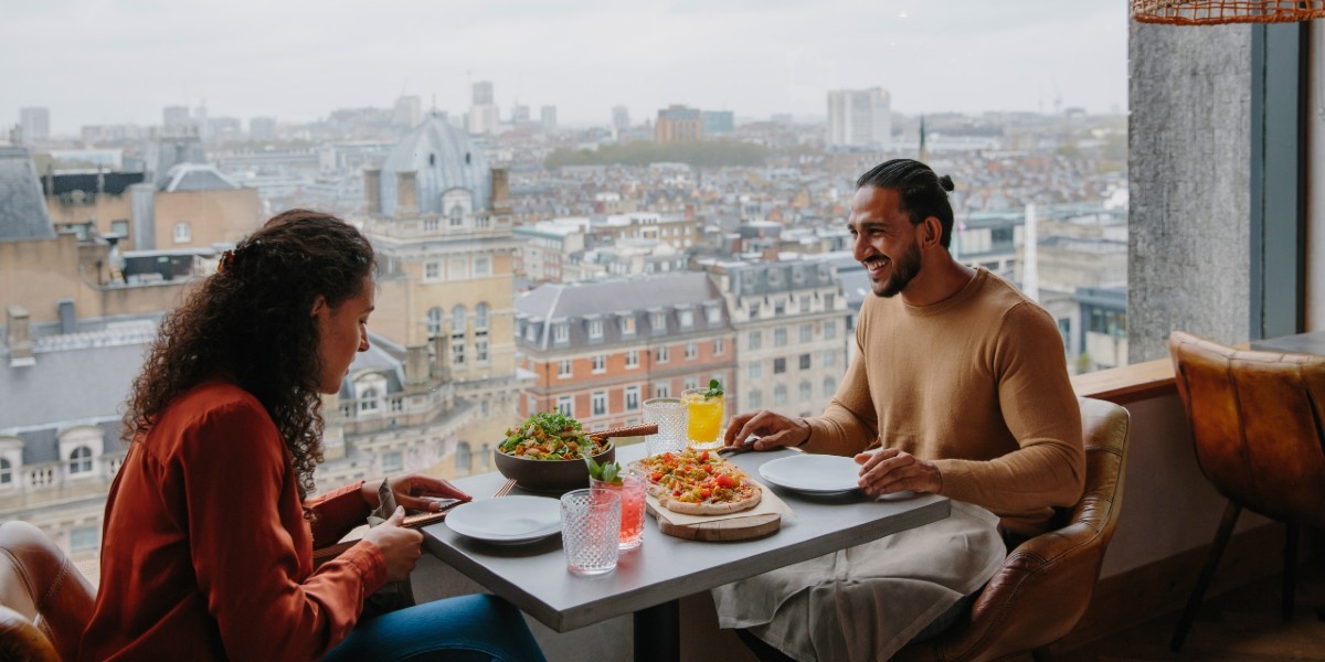 Couple eating in front of a window with a rooftop view