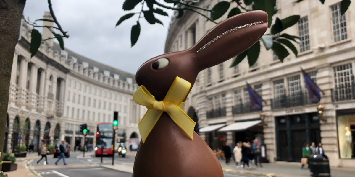 Chocolate rabbit held up against a street view