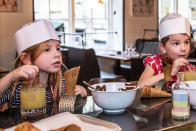 Children in chefs hats sat at a table eating