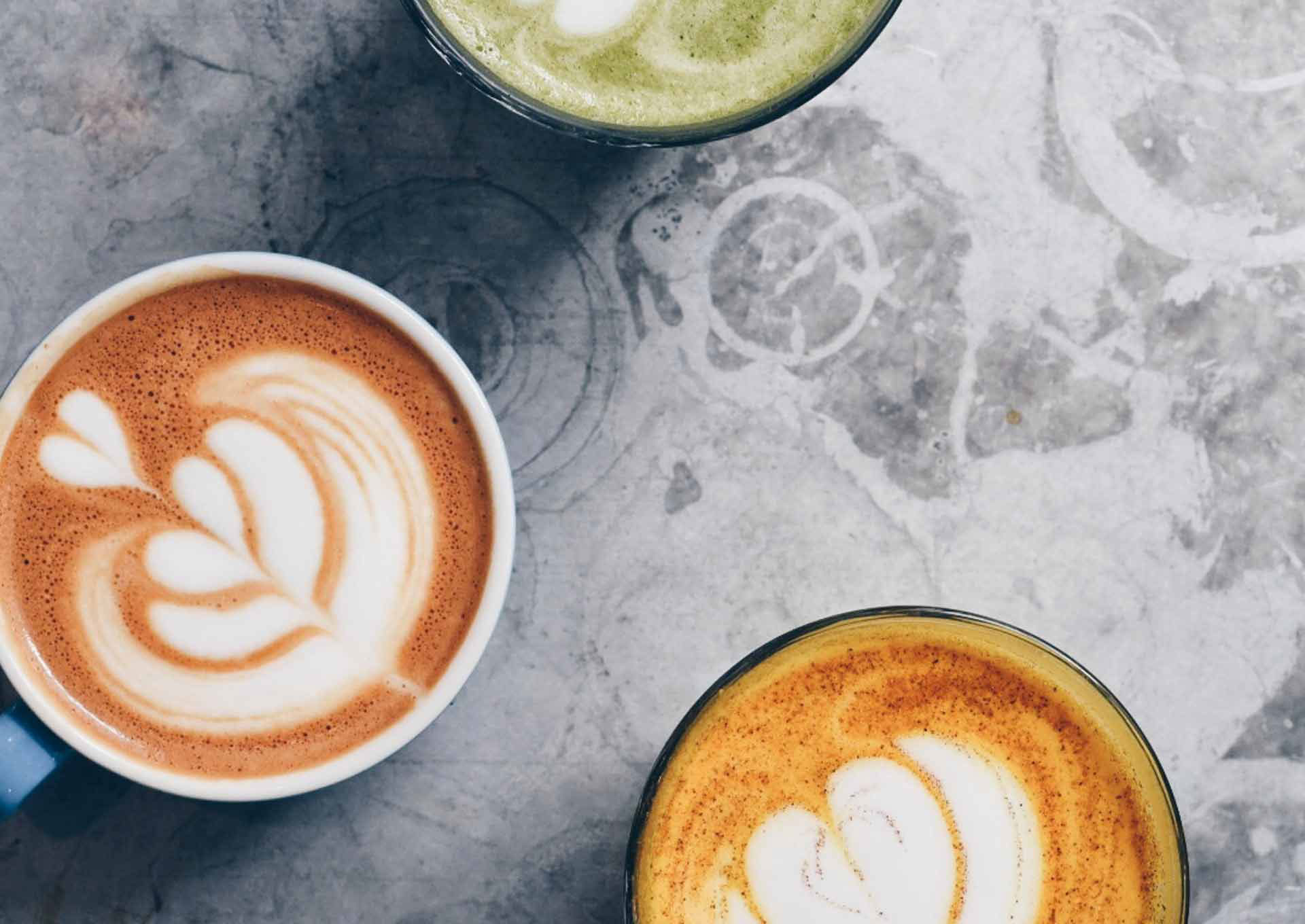 Latte art on top of three different coloured lattes