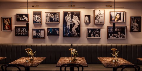 Wall of framed photos above tables