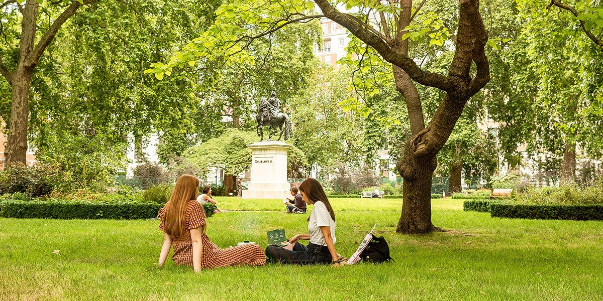 Two women having a picnic on the grass in St James's Square