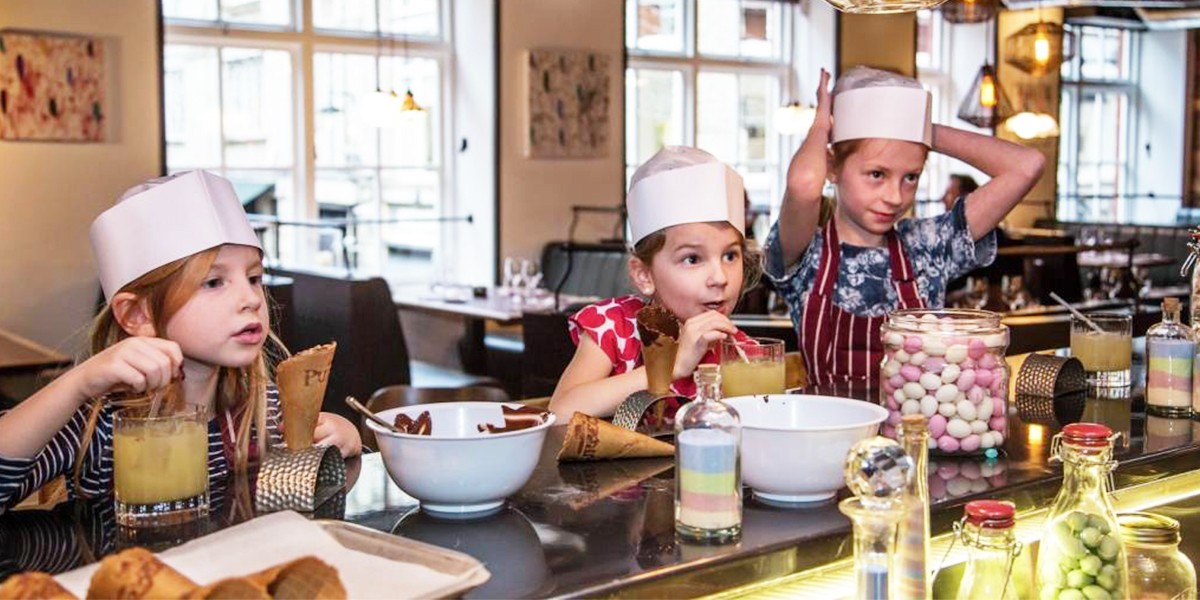 Children in chefs hats sat at a table eating