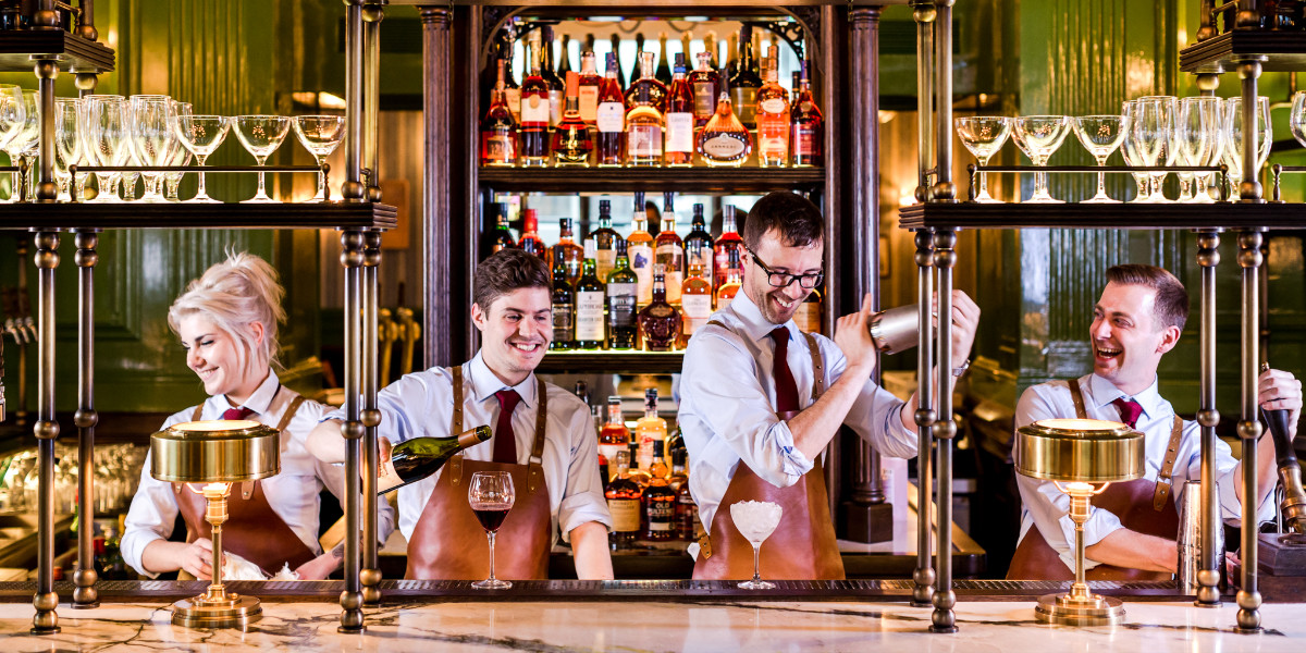 Bar staff at The Wigmore's opulent bar pour from a wine bottle and shake cocktails